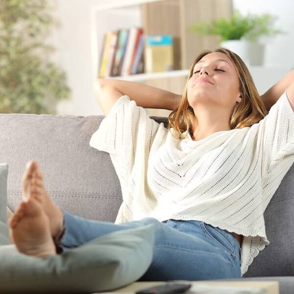 Mulher deitada no sofá, com expressão de alívio, felicidade e relaxamento