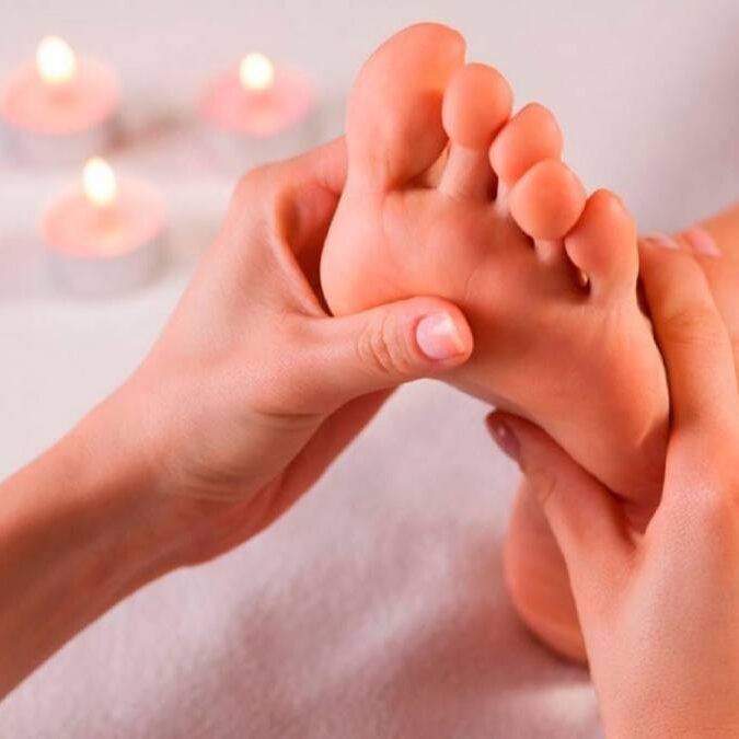 Paciente recebendo uma reflexologia podal (nos pés) pelas mãos de um Massoterapeuta