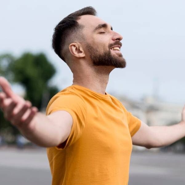 Homem feliz de braços abertos depois um atendimento com massagem e liberação miofascial no Espaço Leocádio