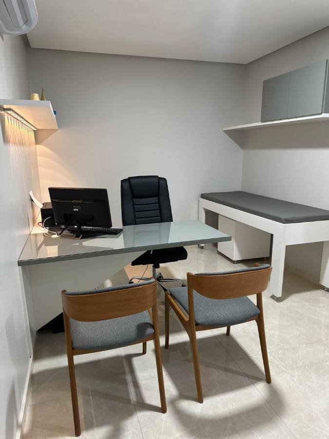 Sala de atendimento do Espaço Leocádio na Clínica Claris, mostrando mesa e cadeiras e maca