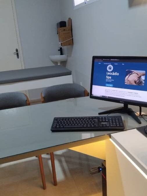 Mesa da Clínica Claris com um computador mostrando o site do Espaço Leocádio