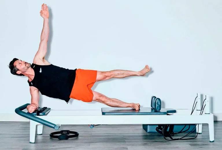 Homem praticando Pilates no aparelho reformer