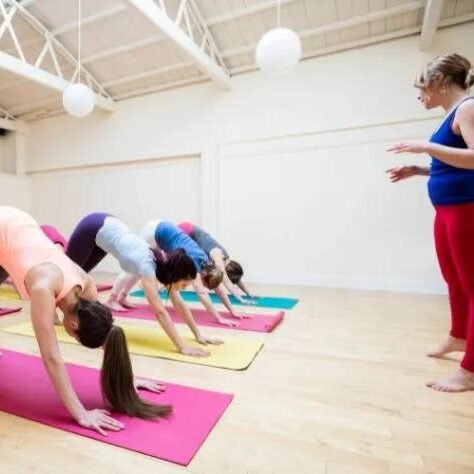 Fisioterapeuta (Instrutora de Pilates) ministrando aula de MAT Pilates em turma reduzida